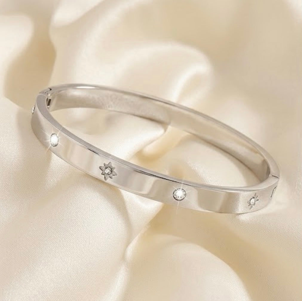 Silver starburst engrave diamond cuff bangle bracelet for women on white satin background.