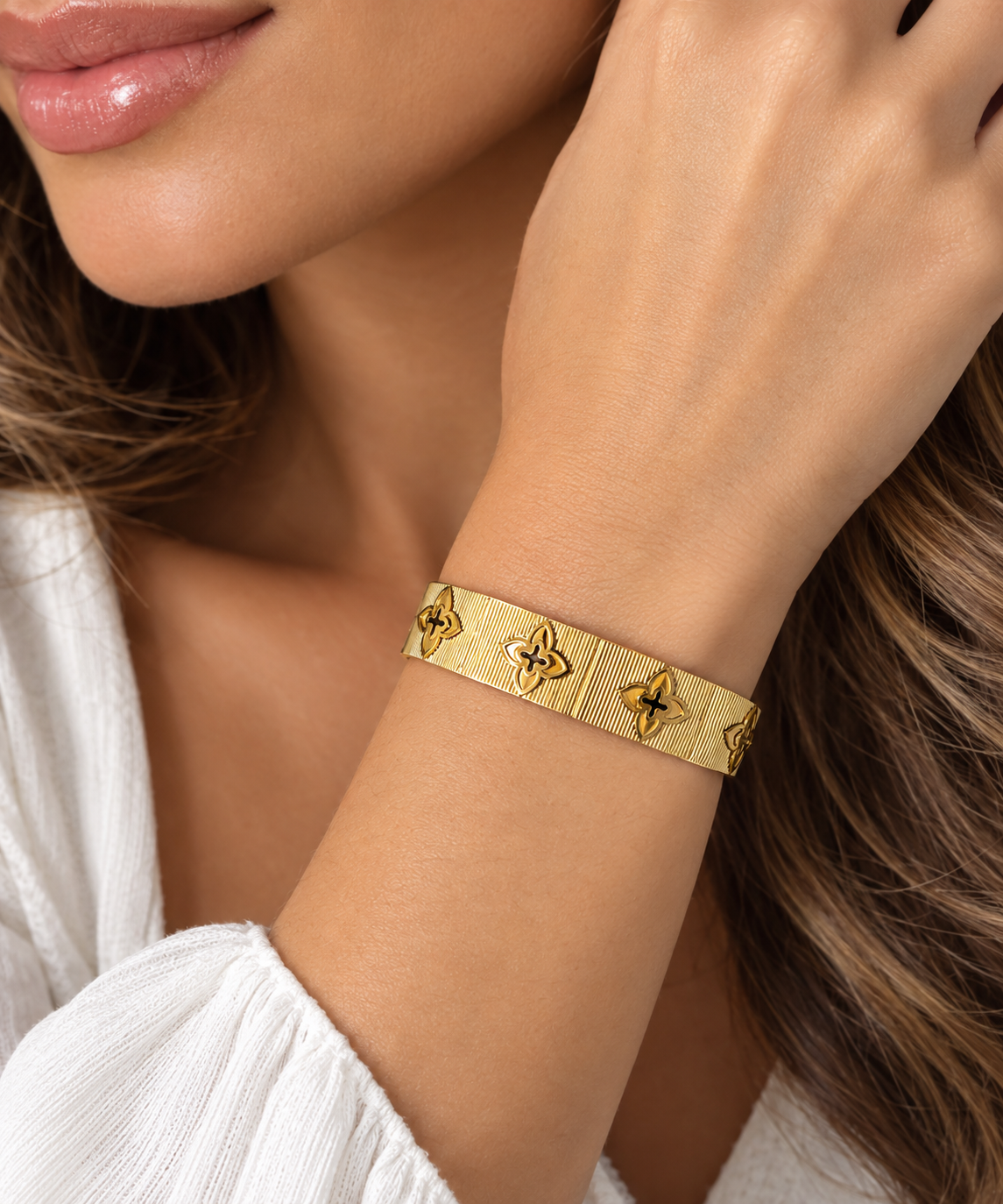 Gold textured floral clover bangle bracelet lifestyle model showcase on wrist.
