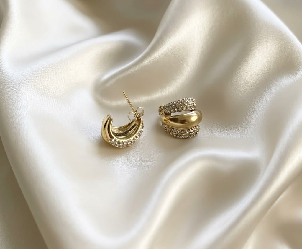 Gold triple row pave cz huggie hoop earrings chunky statement jewelry on white satin background.