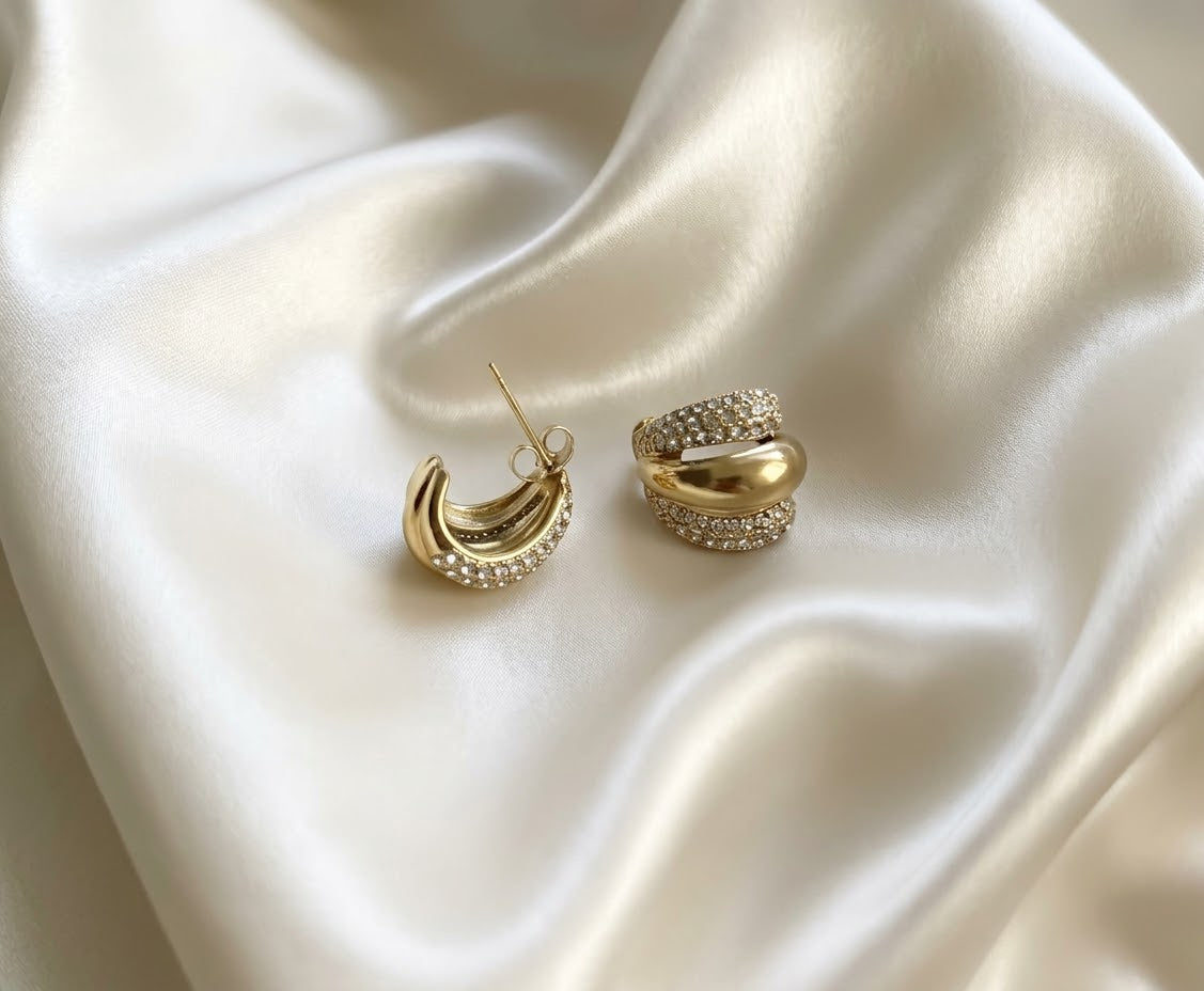 Gold triple row pave cz huggie hoop earrings chunky statement jewelry on white satin background.