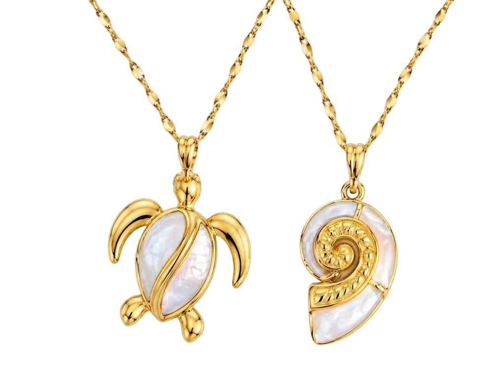 Product photo of two gold pendants on twisted link chains set against a plain white background. The left pendant is shaped like a sea turtle with gold fins and a white enamel body bisected by a curved gold accent. The right pendant is shaped like a spiral nautilus seashell made with white enamel panels and detailed gold scrollwork.