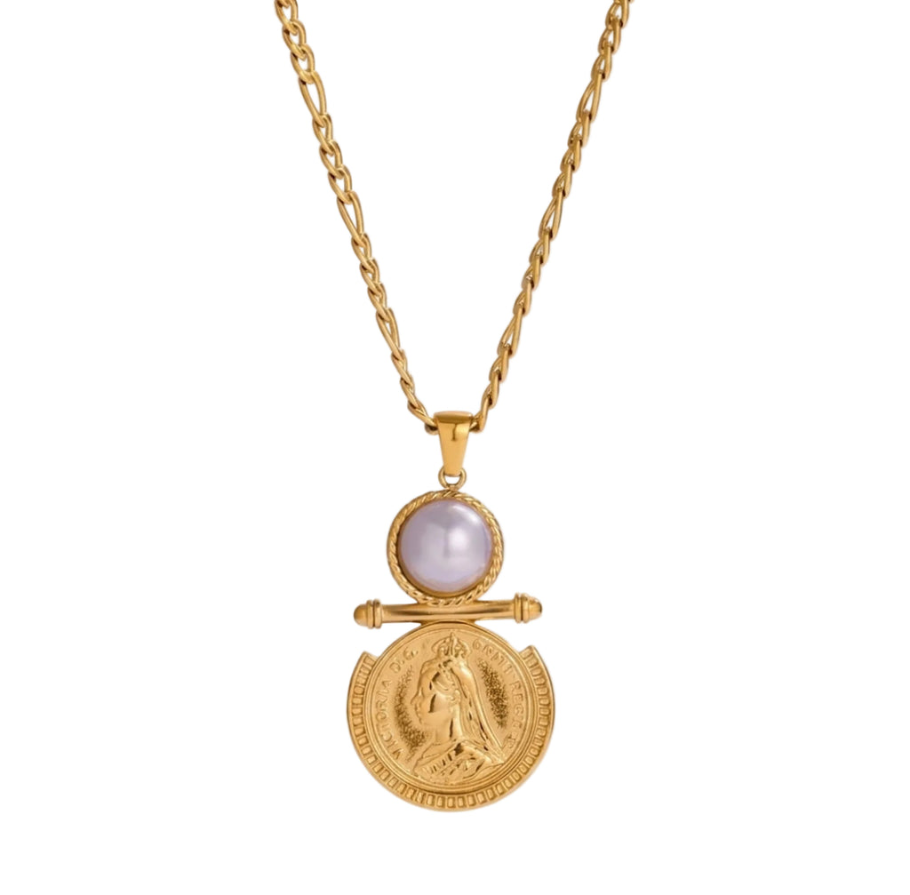 A gold pendant necklace featuring a round white pearl and an antique gold coin pendant, displayed on a clean white background with a subtle reflection.
